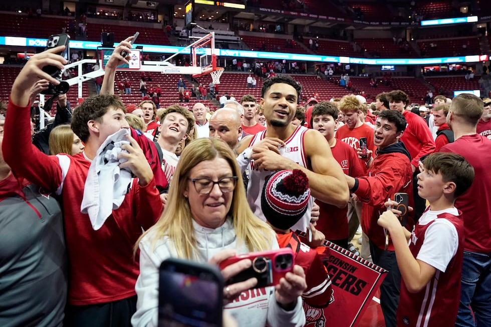 Wisconsin guard Nick Boyd, center, walks off the court while surrounded by fans after...
