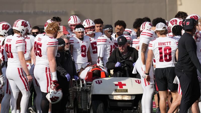 Wisconsin running back Gideon Ituka is surrounded by teammates as he is carted off the field...