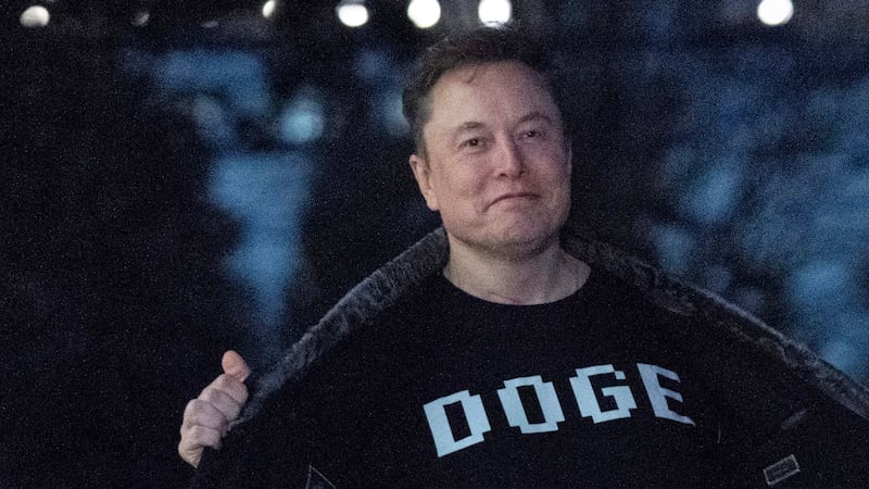 Elon Musk flashes his t-shirt that reads "DOGE" to the media as he walks on South Lawn of the...